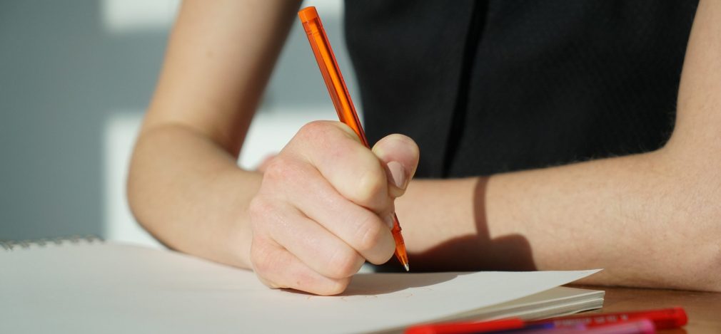 Woman writes a note with an orange pen